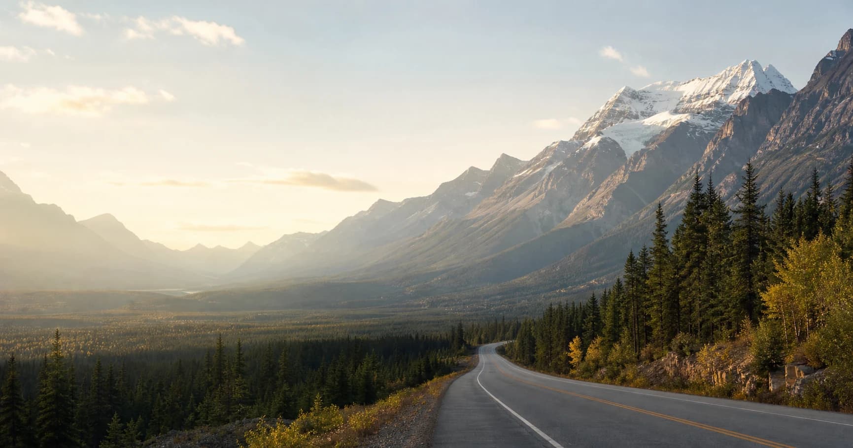 Estrada entre uma floresta e montanhas canadenses iluminadas pelo sol